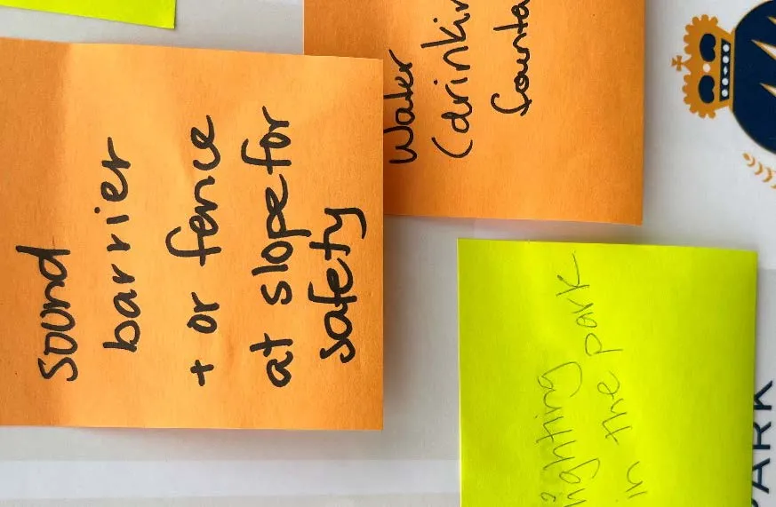 Close-up of sticky notes mentioning a sound barrier or fence, water fountain, and lighting in the park