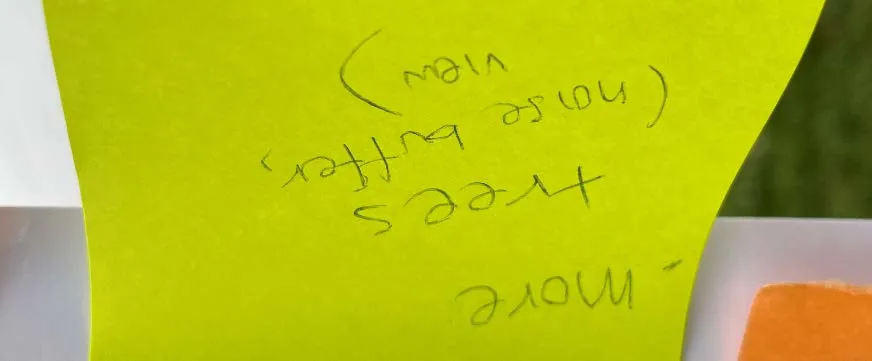 Close-up of a sticky note mentioning more trees for a noise buffer and view