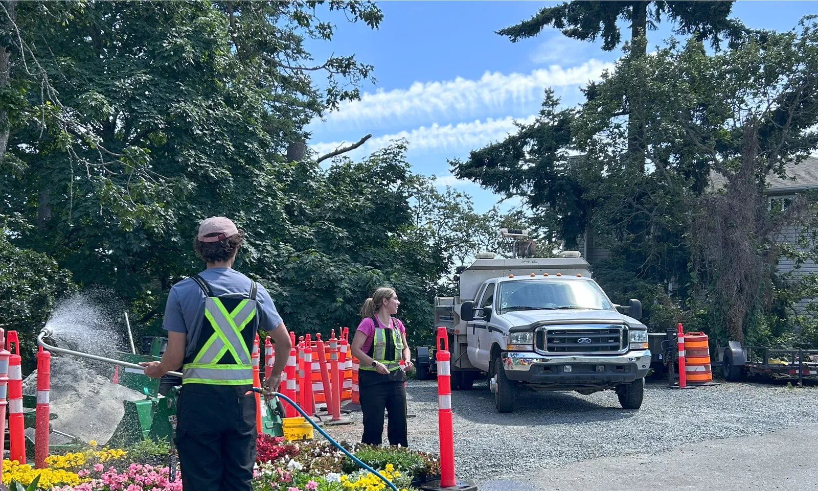 Photo: Summer crew working in Parks yard - staff members watering flower beds near a utility truck