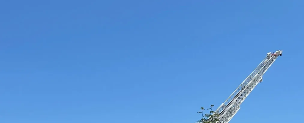 Top of fire ladder against a clear blue sky