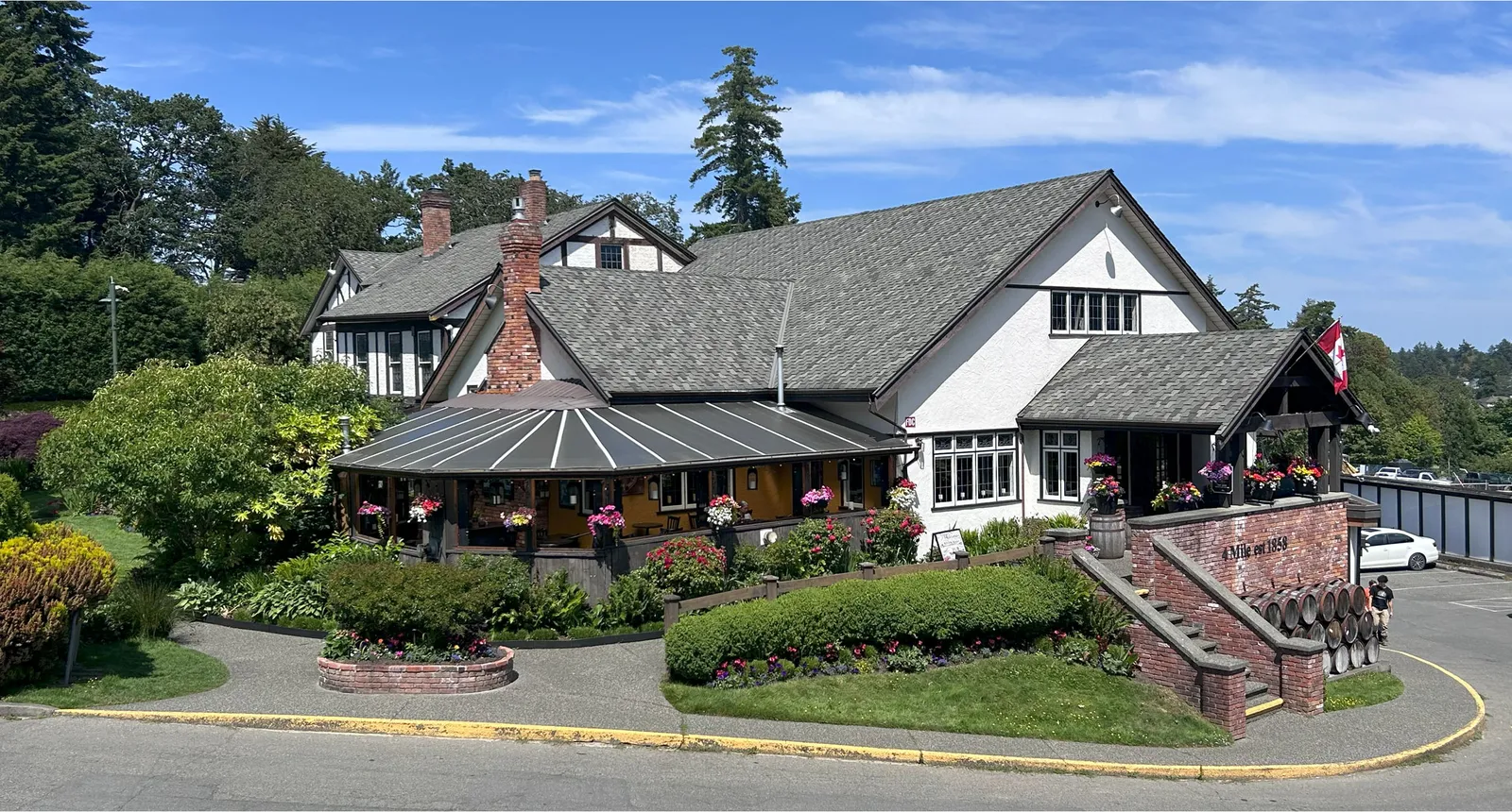 Photo of Four Mile Pub, a historic white building with dark trim and flower baskets, established in 1858