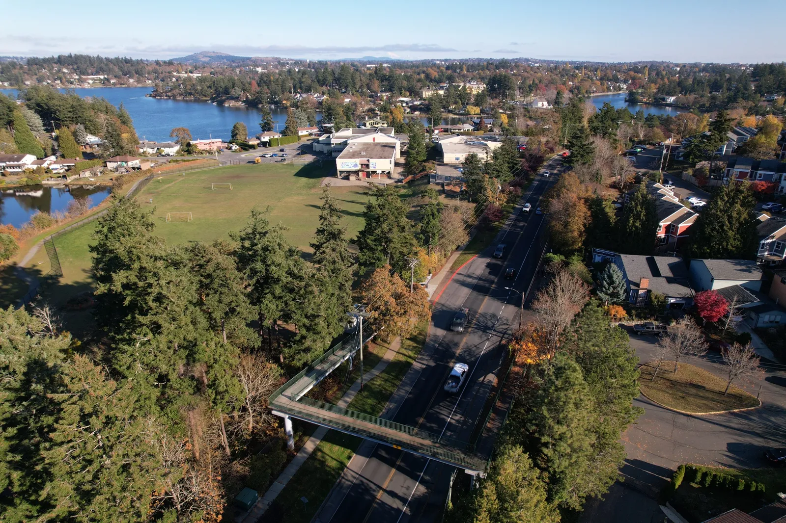 Aerial view of View Royal featuring a pedestrian bridge, a sports field, and residential areas near the water
