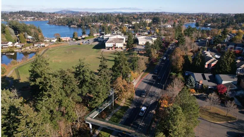 Aerial view of View Royal showing a green field, residential buildings, and a pedestrian overpass over a road