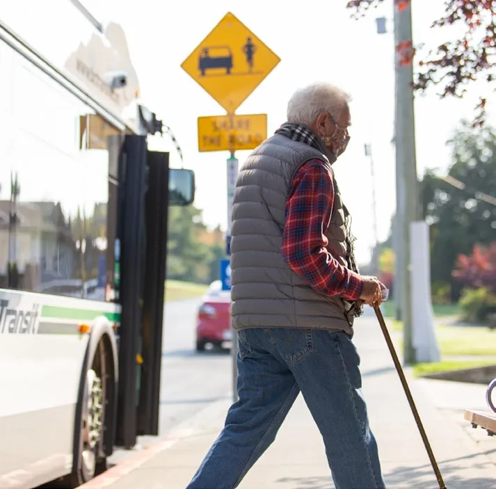 Senior man with a cane boarding a bus