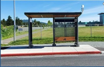 Photo of a modern BC Transit bus shelter with a wooden-style roof and seating