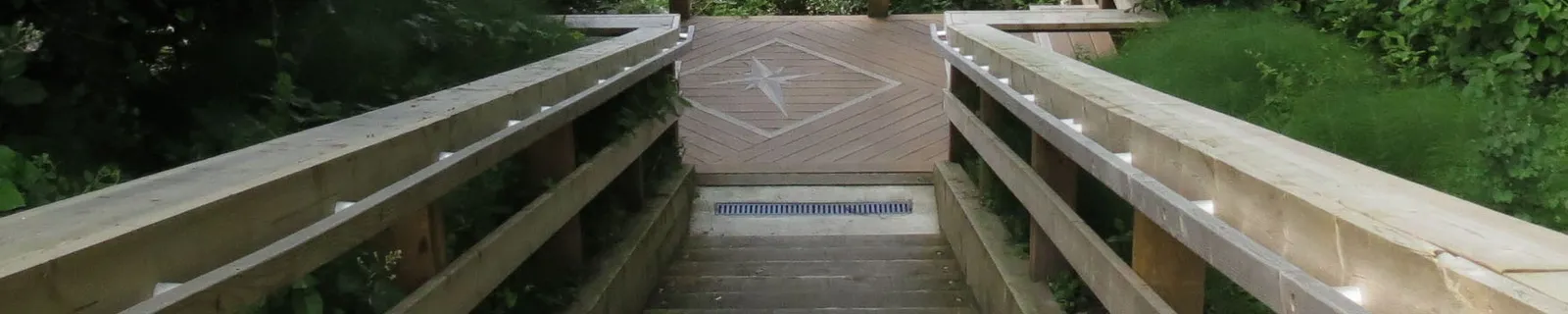 Looking down a flight of wooden stairs to a landing with a compass rose inlay