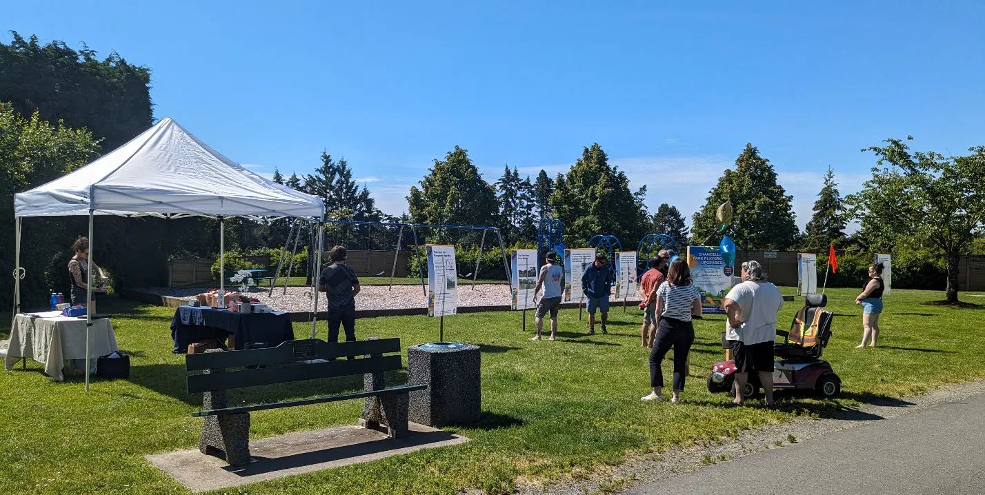 People attending the Chancellor Park open house on Saturday, June 8, 2024, with informational boards and a tent set up on a grassy field