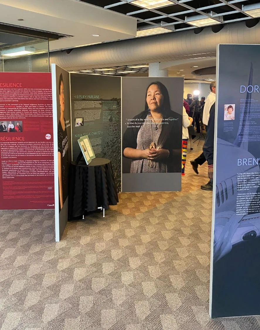 An exhibition display within a library featuring large portrait panels and descriptive text boards.