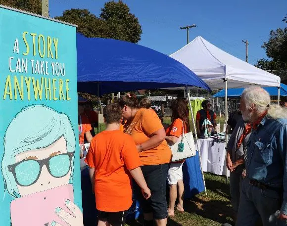 An outdoor promotional banner featuring the slogan "A STORY CAN TAKE YOU ANYWHERE."