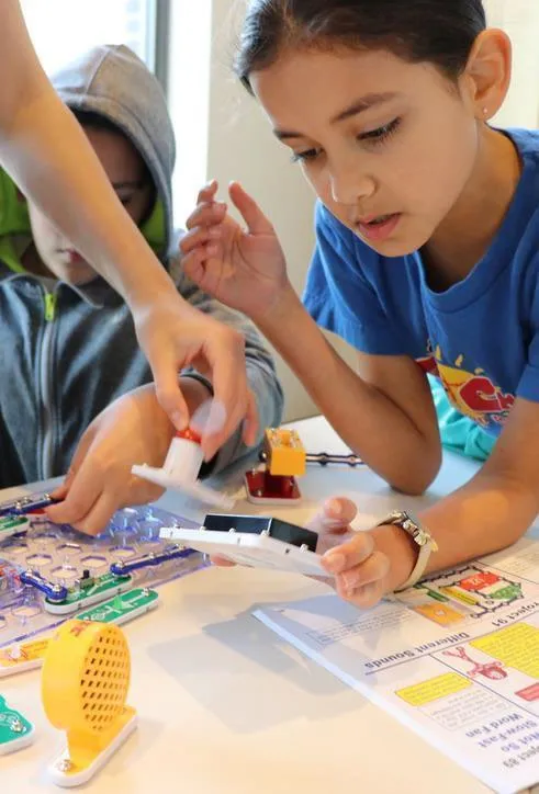 Two children working together on an electronic educational circuit building project.