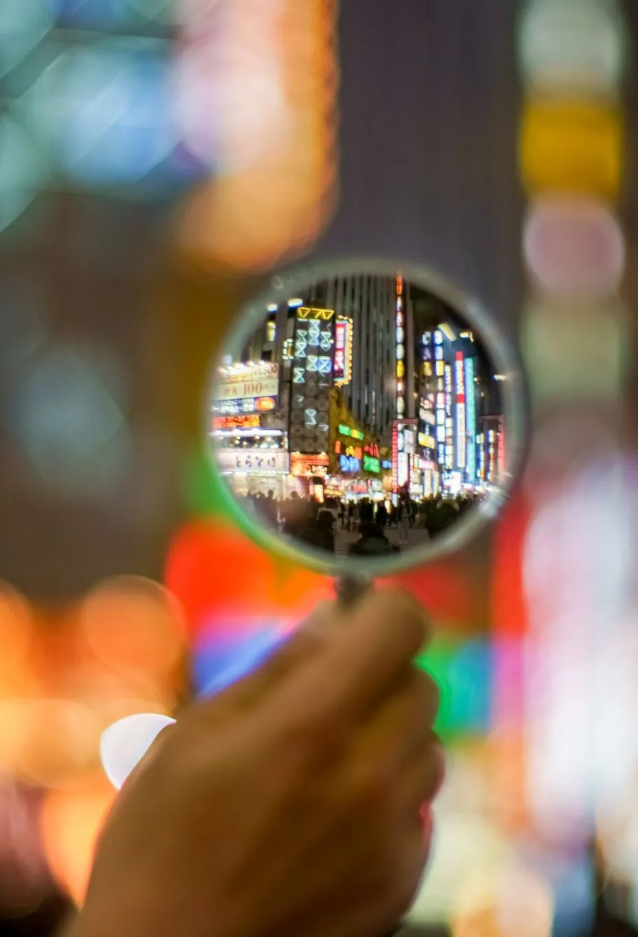 A magnifying glass held over a blurred, brightly lit city street at night