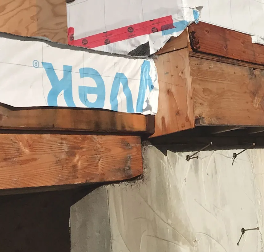 Close-up photo of wooden framing with structural hardware and light strings