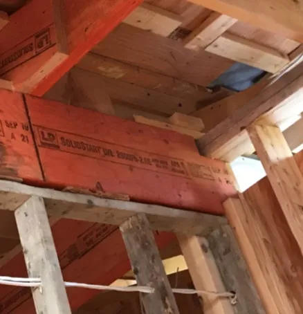 Photo of a wall section showing wooden studs and a lintel over an opening