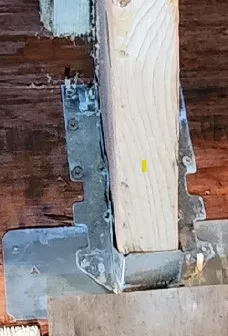 Close-up photo of a metal structural connector installed on a wooden stud