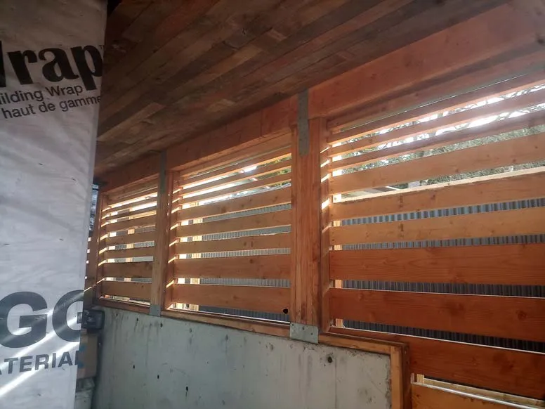 Interior view of wooden slat wall with building wrap labeled "rap"