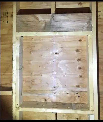 Wide interior view of house framing with plastic covering the floor