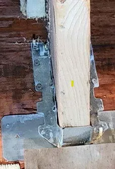 Joist hangers and structural strap on a wooden beam with string lights