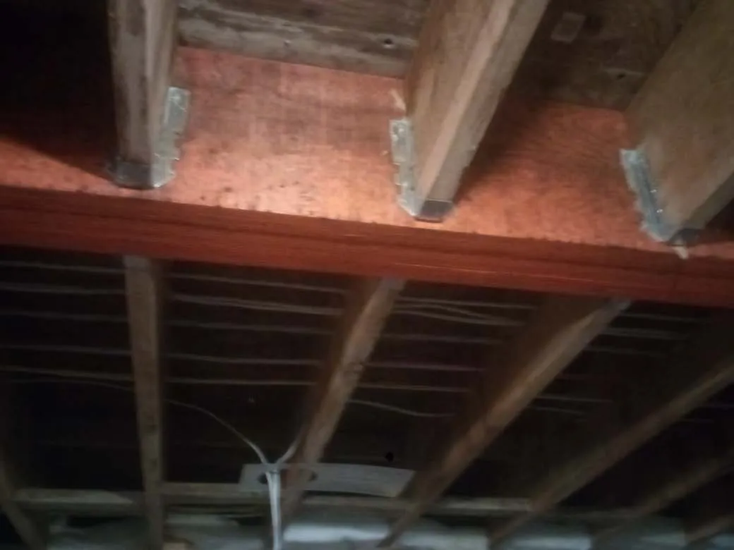 Joist hangers and structural strap on a wooden beam with string lights