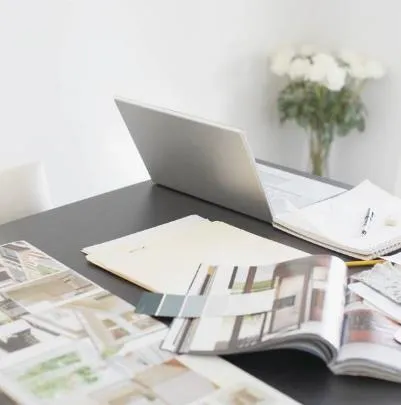 Desk with a laptop, architectural sketches, and folders