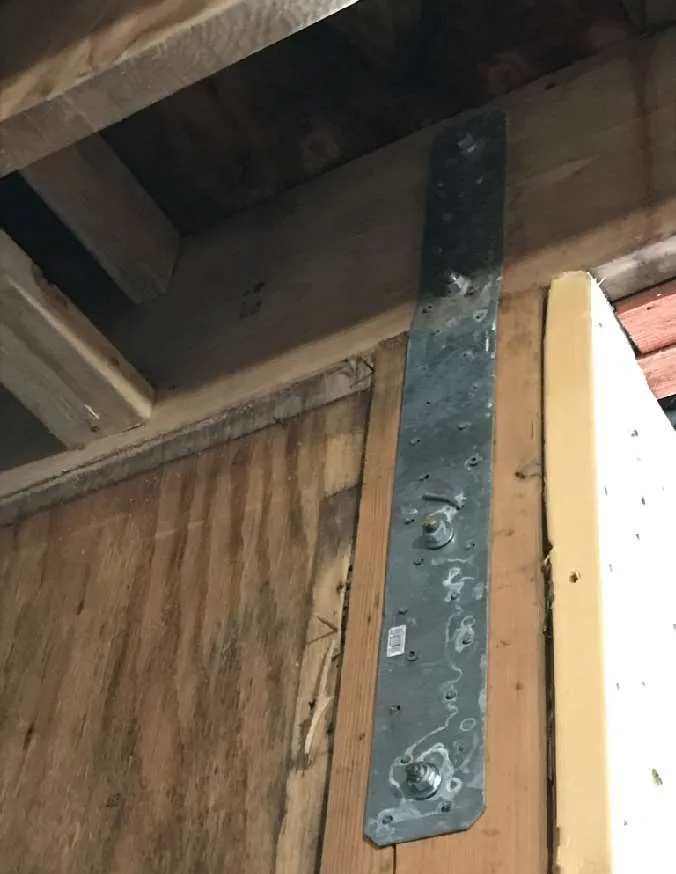 Underside view of wooden floor joists and plywood subfloor with extensive dark staining.