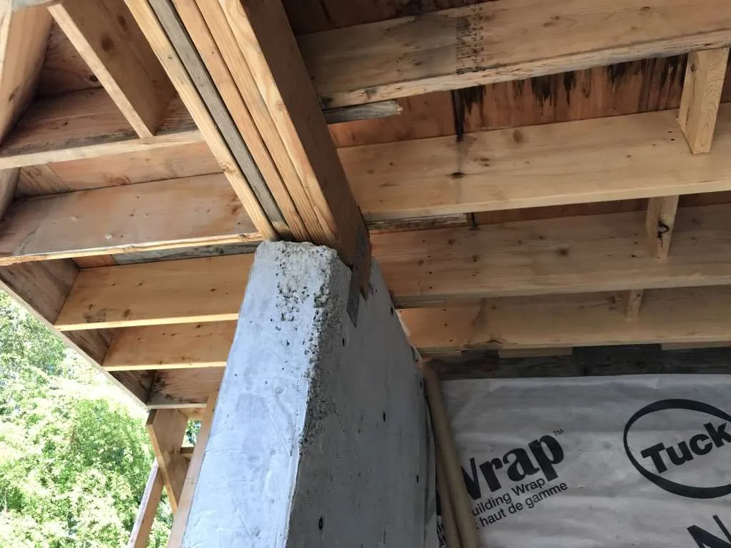 Wooden beams resting on a post with some orange-painted beams.