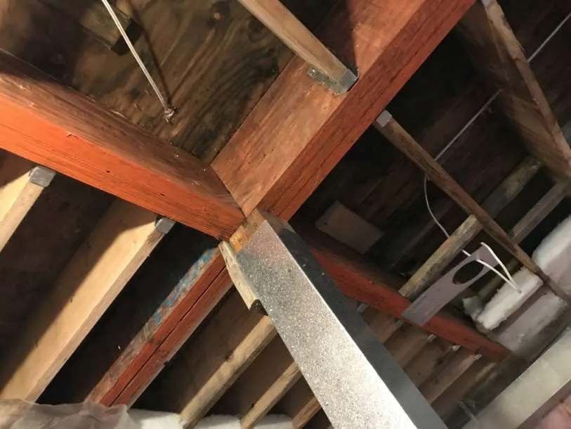 Ceiling joists and a wall with pink fiberglass insulation.