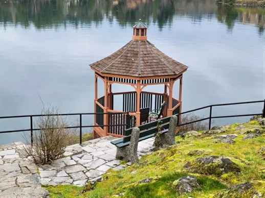 Exterior view of the gazebo on a rocky shoreline next to a stone path and bench
