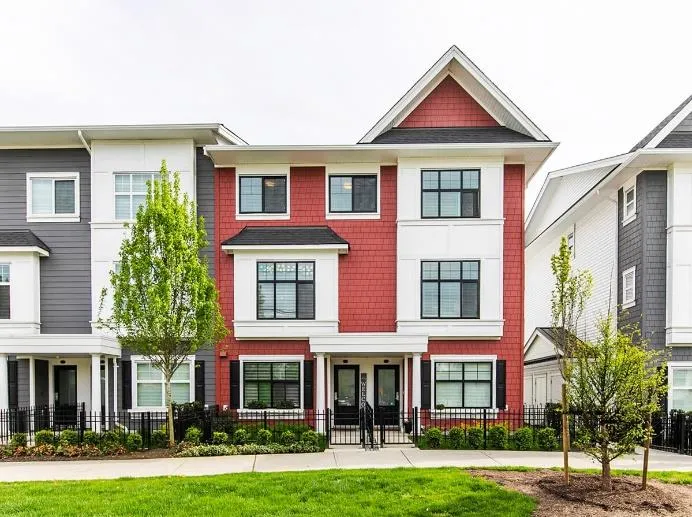 A row of modern three-story townhomes with red and grey siding