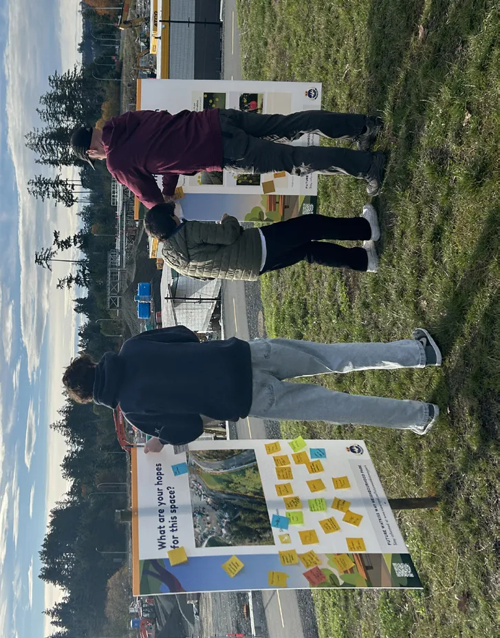 Community members reviewing a "What are your hopes for this space?" feedback board covered in sticky notes during the on-site open house