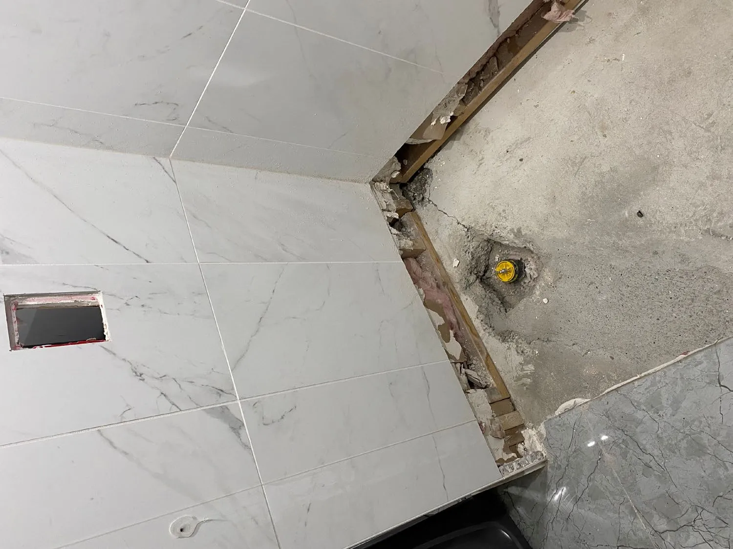 View behind an appliance showing a gas line and metal vent pipe