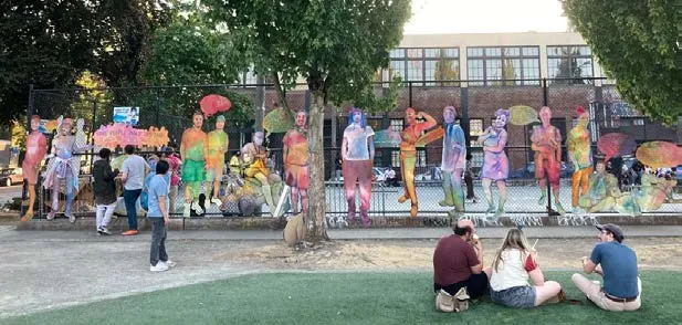 Large mural on a corner building featuring people and forest elements in vibrant colors