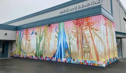 Public art installation featuring several colorful, human-shaped figures on a fence