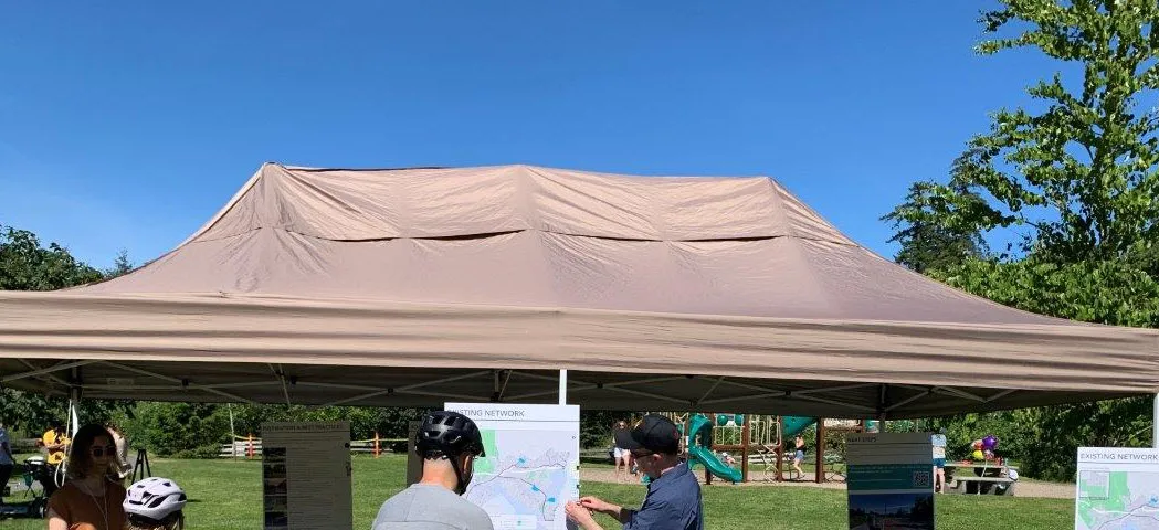 The top of a tan event tent set up outdoors in a park-like setting