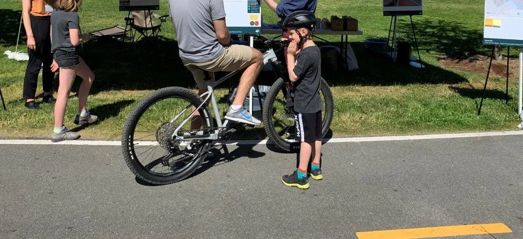 Residents, including a person on a bicycle, engaging with staff at an information booth at the Active Transportation Network Plan Ideas Fair