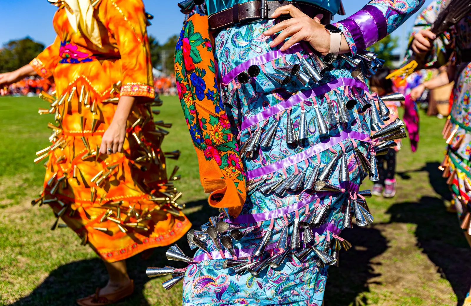 Dancers in colorful regalia featuring metallic jingles
