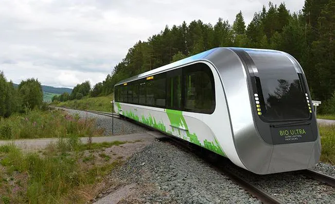 Rendering of a sleek Bio Ultra light rail vehicle on a track through a forested landscape