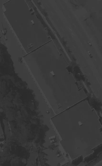 Aerial view of a large building with a dark roof and adjacent parking