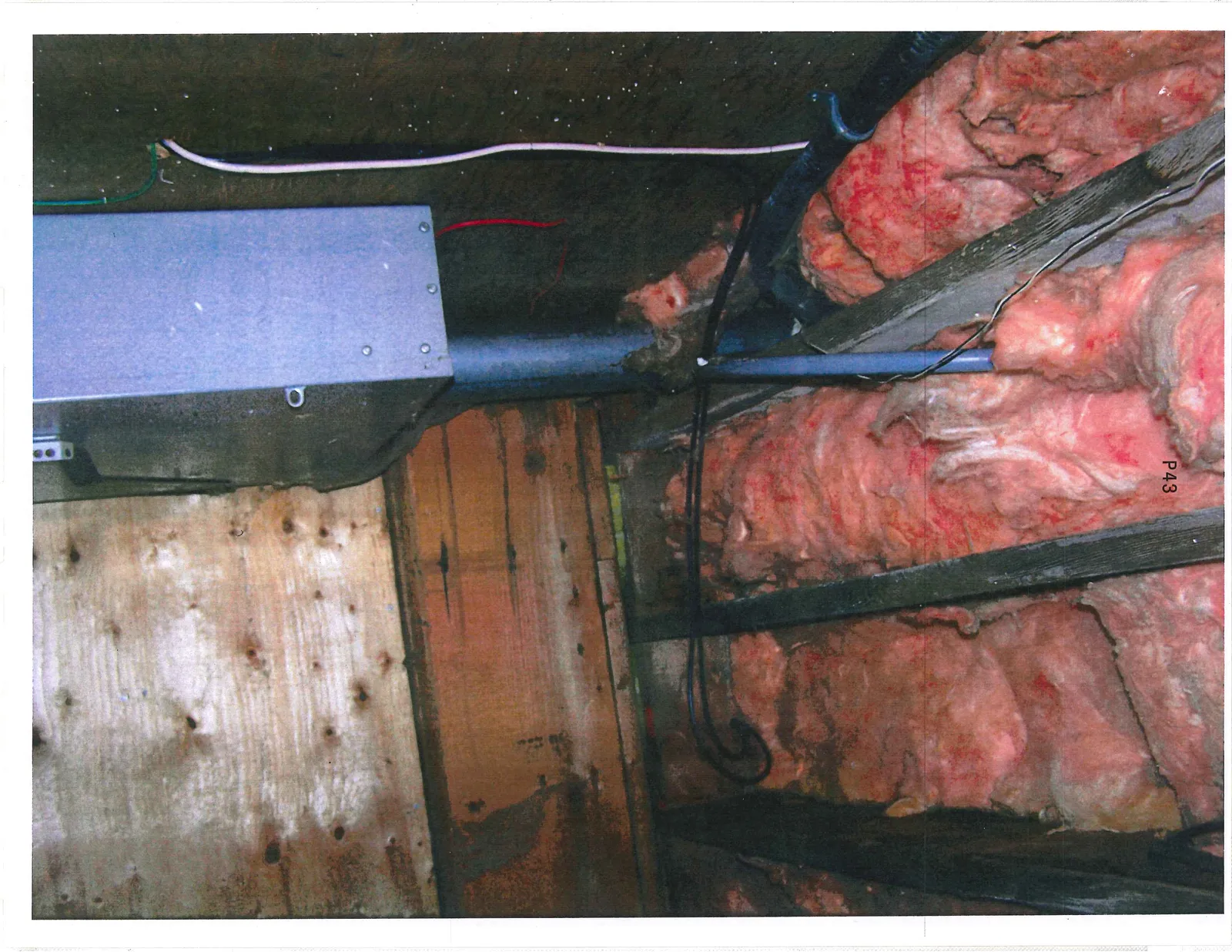 Exposed pink insulation and electrical wiring in a crawlspace or ceiling