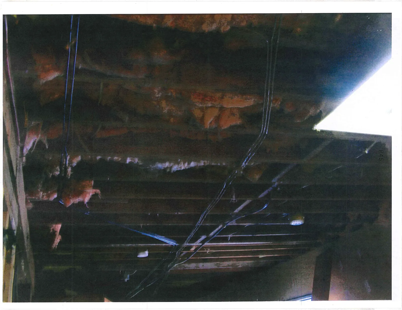 Exposed wall studs with insulation and hazardous-looking disorganized wiring