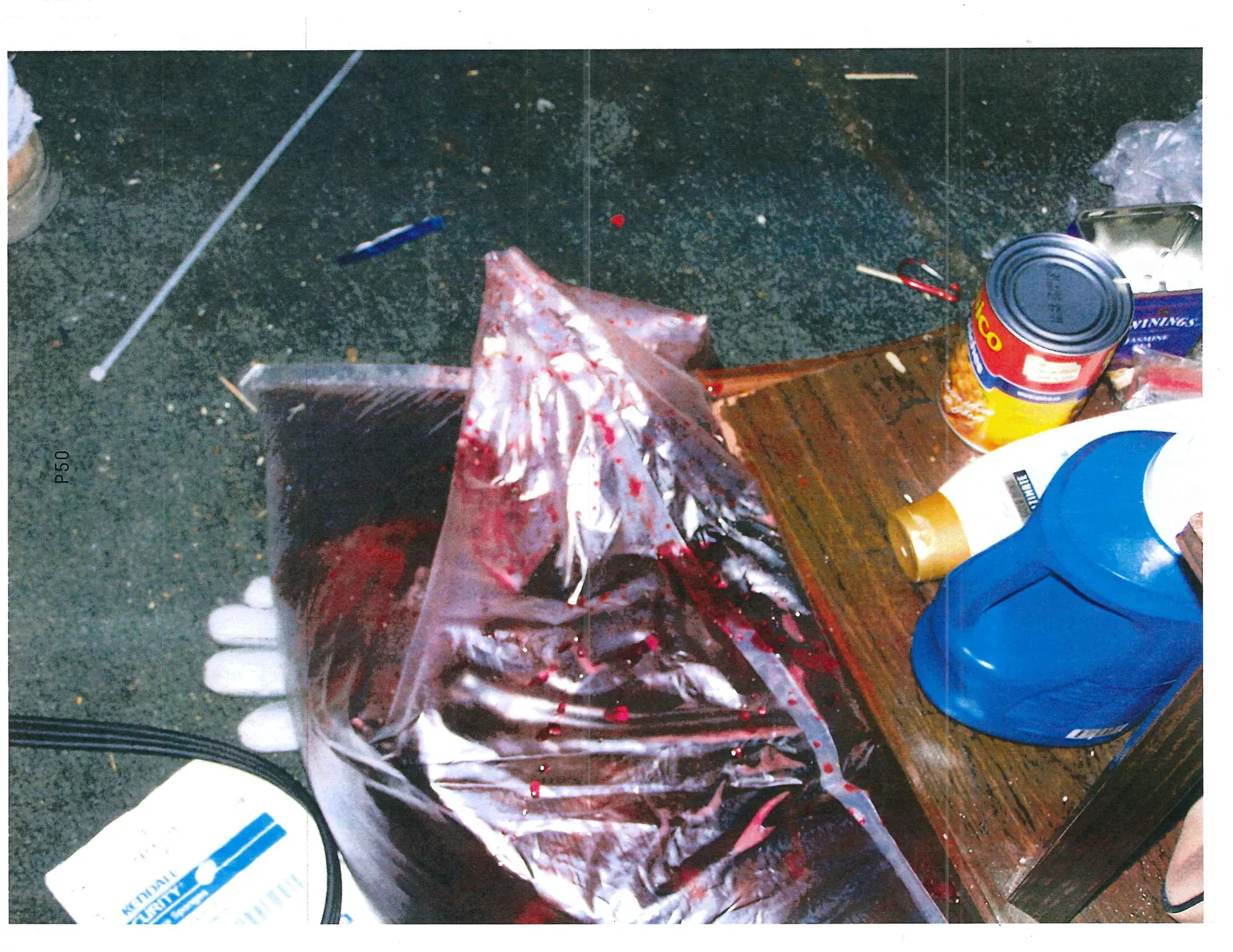 Large plastic bag containing a dark red liquid on the floor near food and household supplies