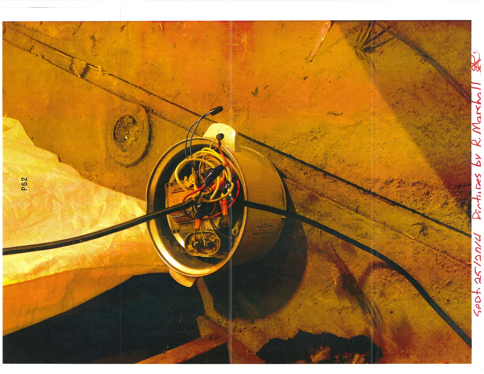 A metal pot containing a tangle of electrical wires and components on a concrete floor.