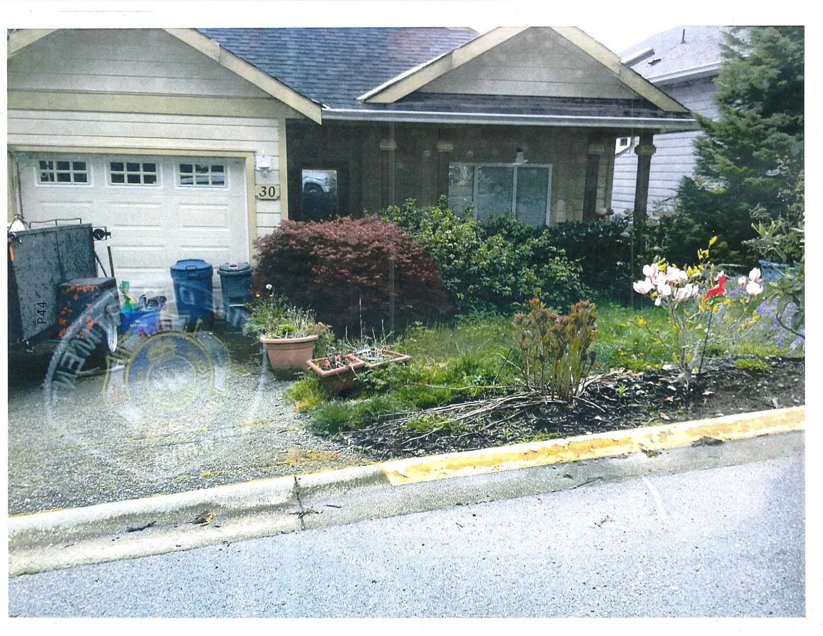 Front view of house 30, showing the garage door, a front window, and landscaped garden beds with white and pink flowers.