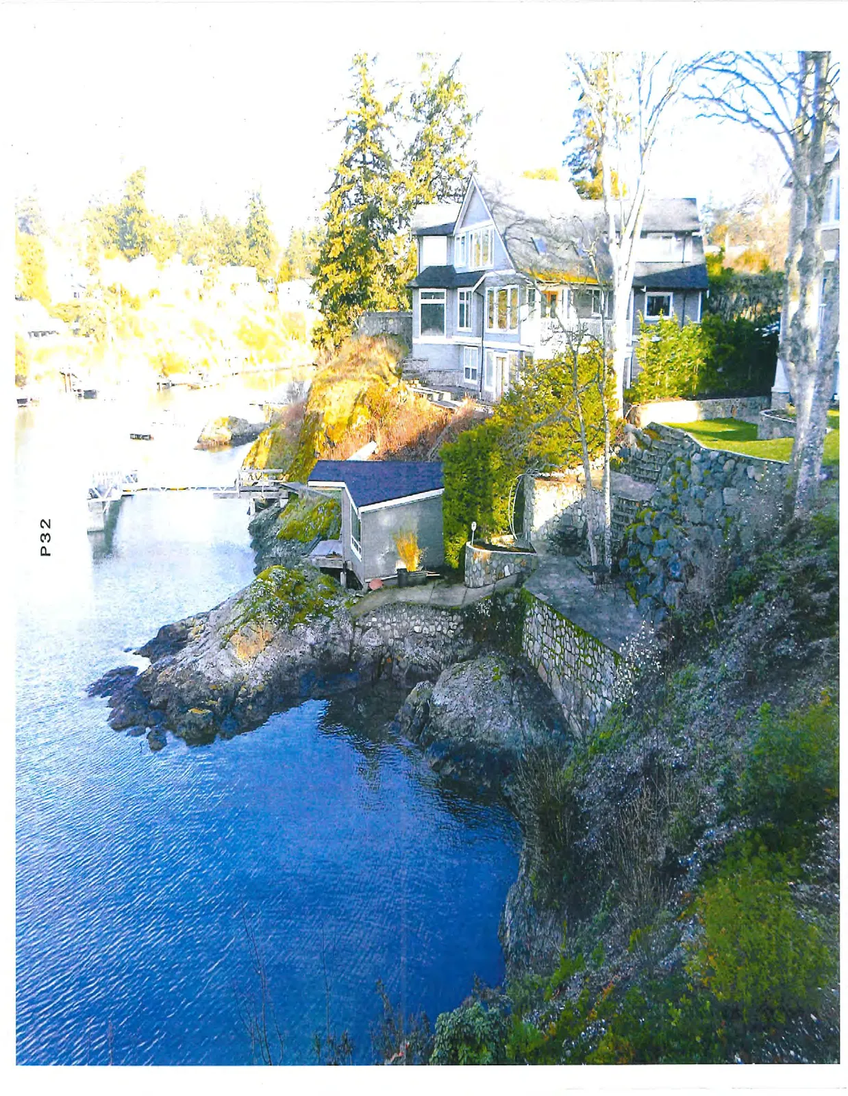 Waterfront house on a rocky cliff overlooking a cove with a small dock.