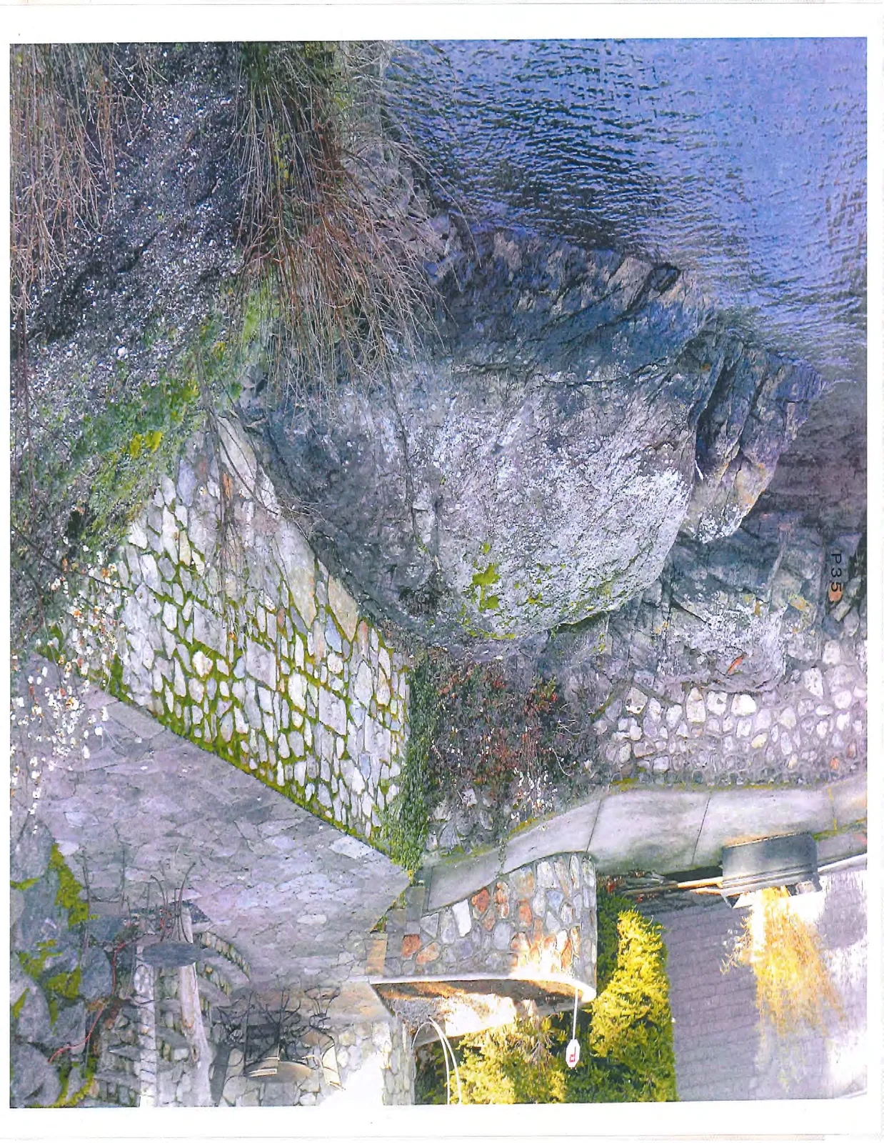 View of a stone-paved patio area built around a large natural rock outcrop.
