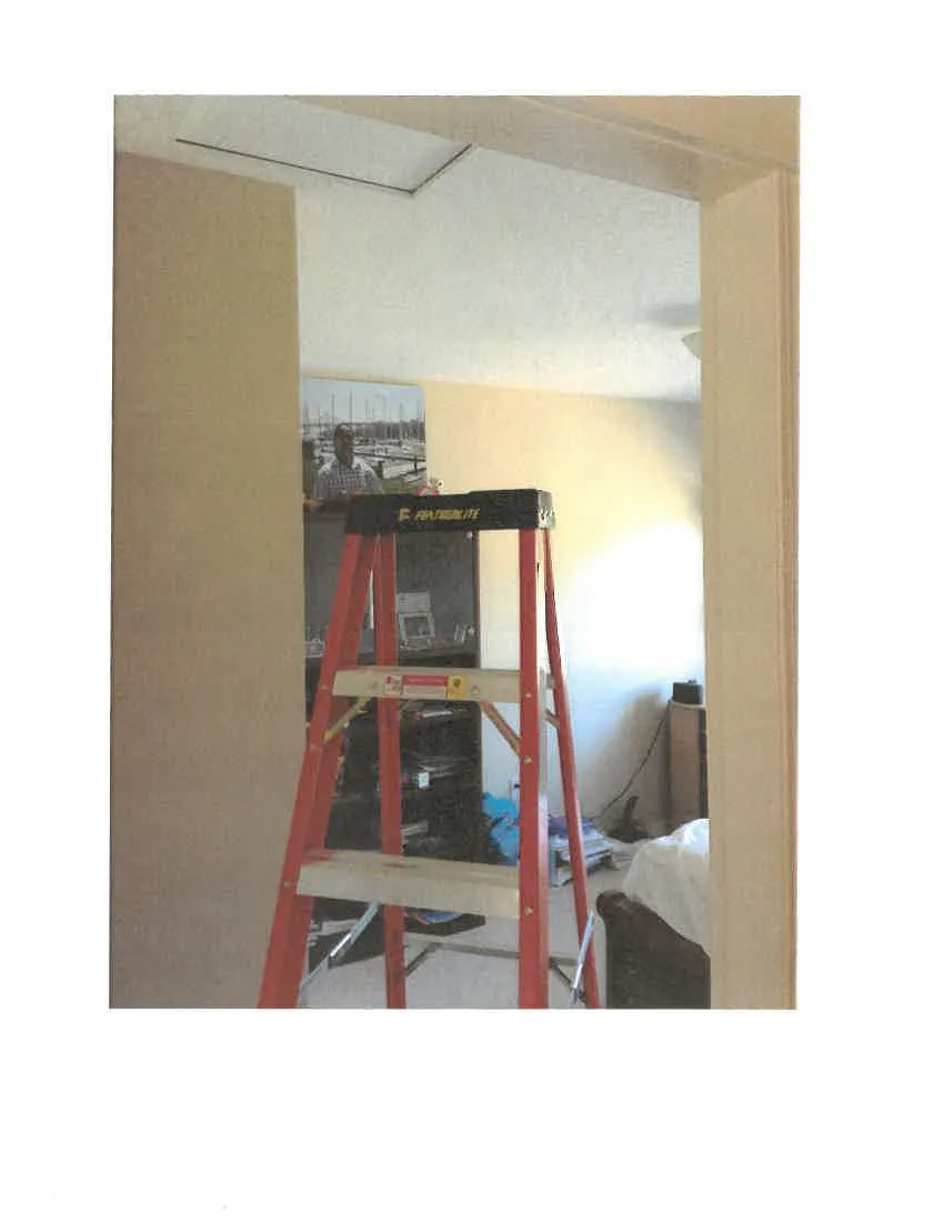 Step ladder set up in a bedroom directly beneath an open attic access hatch