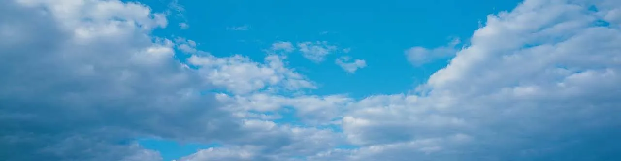 Bright blue sky with large, wispy white clouds
