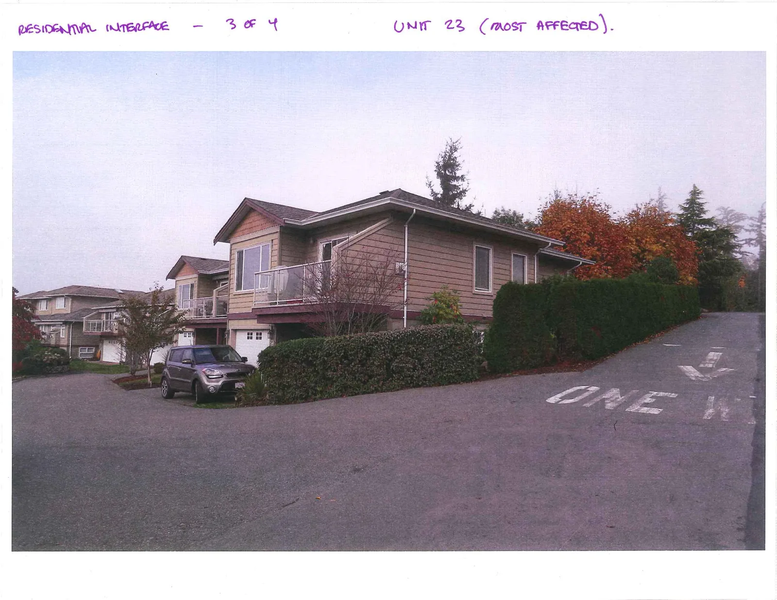 Exterior view of Unit 23 with a vehicle parked in front and "ONE WAY" directional markings on the pavement.