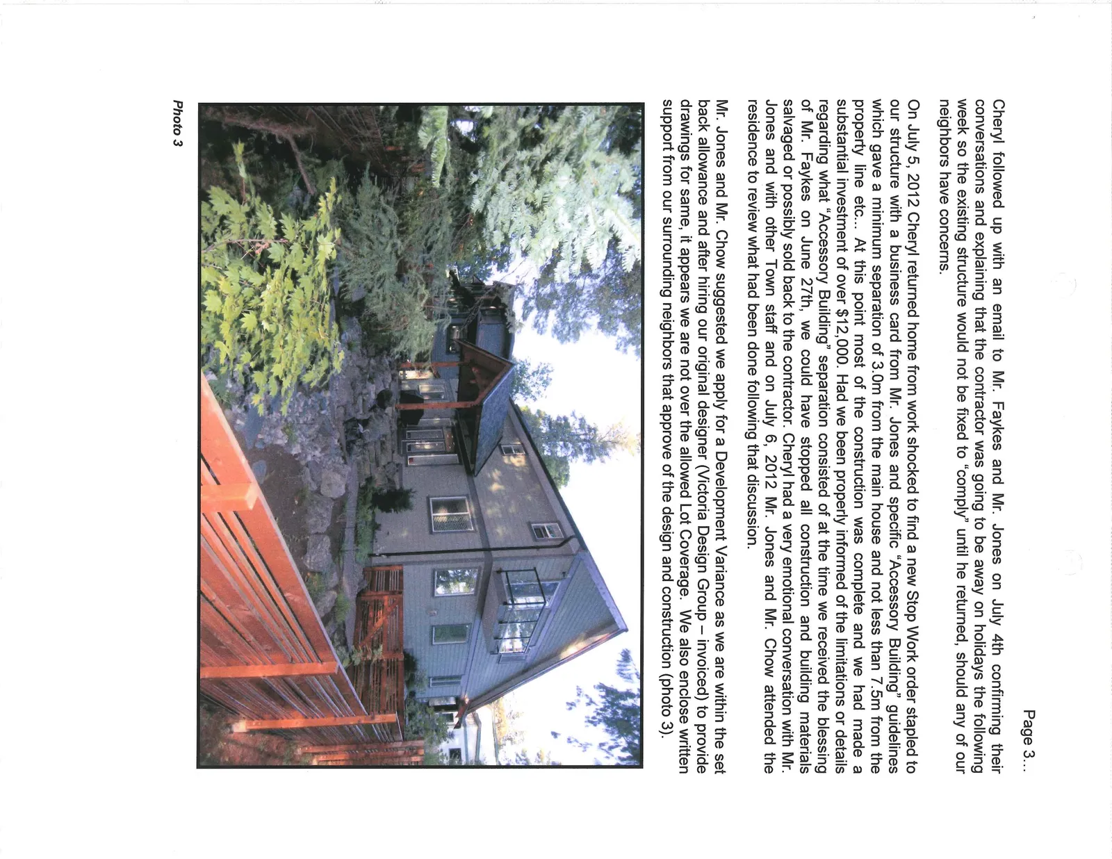 Photo 3 - Perspective view of the rear and side of the residence showing the completed exterior structure, outdoor stairs, and matching wooden fencing