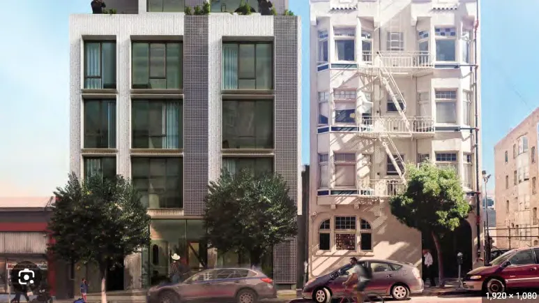 Photo of a modern apartment building with a white geometric facade and recessed balconies.