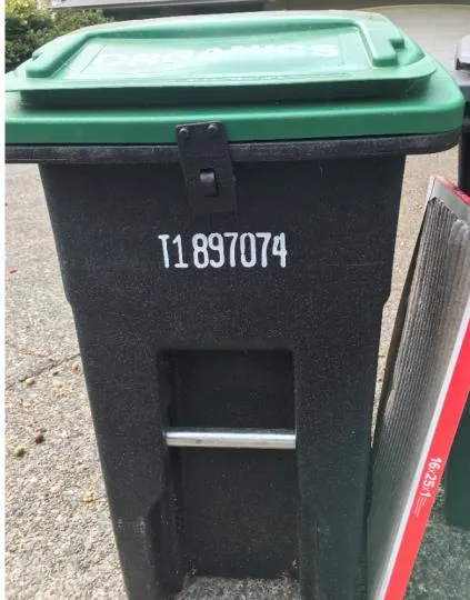 A black organics bin with a latch mechanism and the number T1 897074